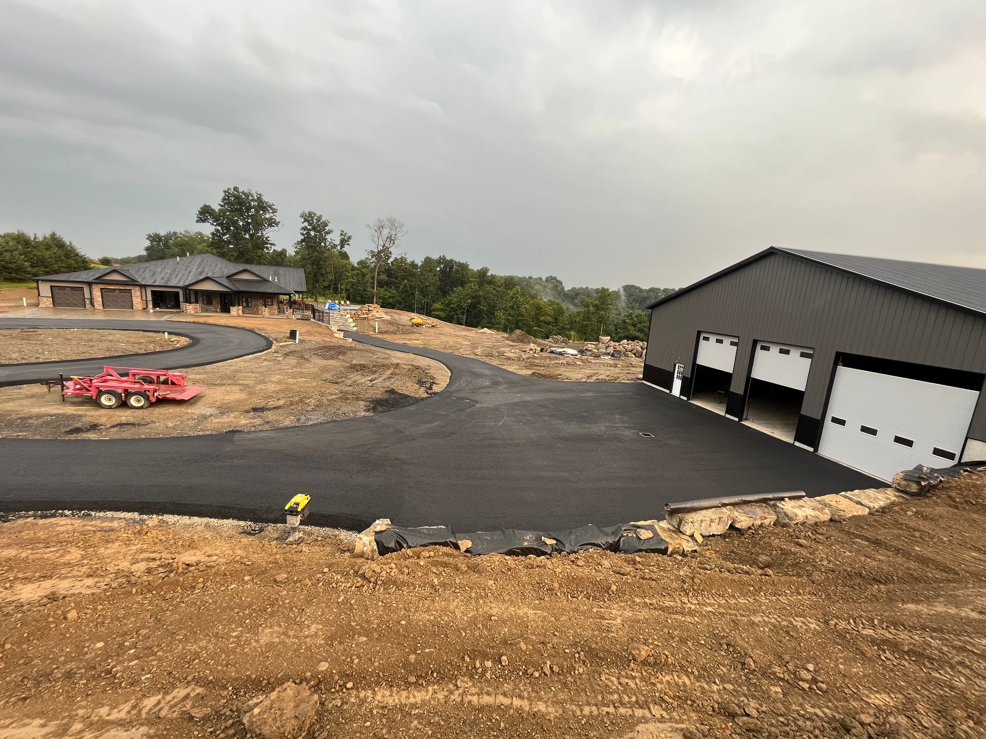 A red car is parked on the side of a road next to a garage.