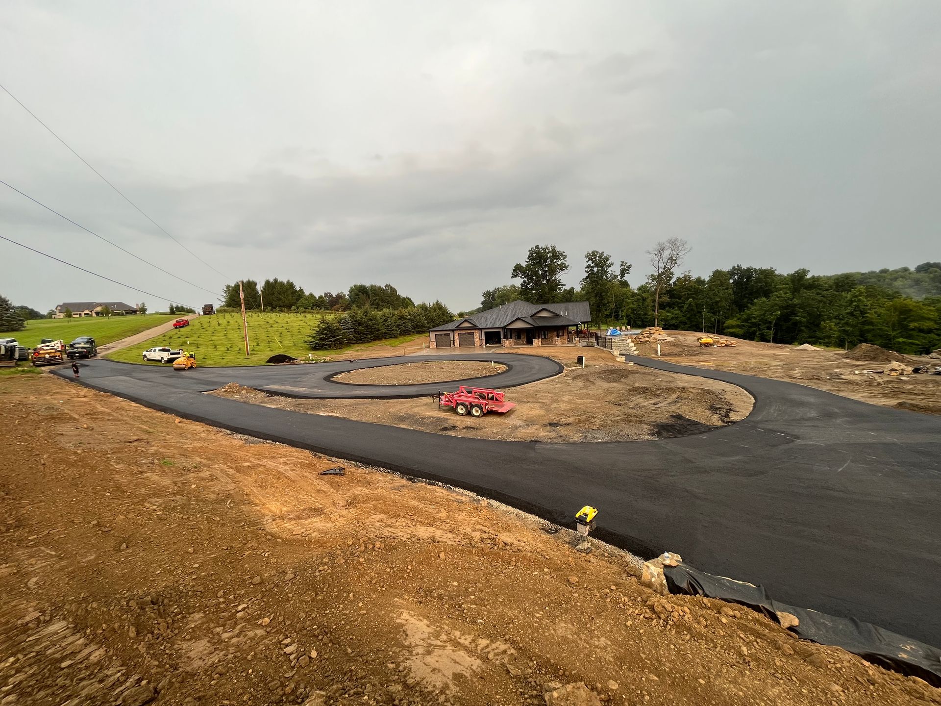 A road is being built in a rural area with a house in the background.
