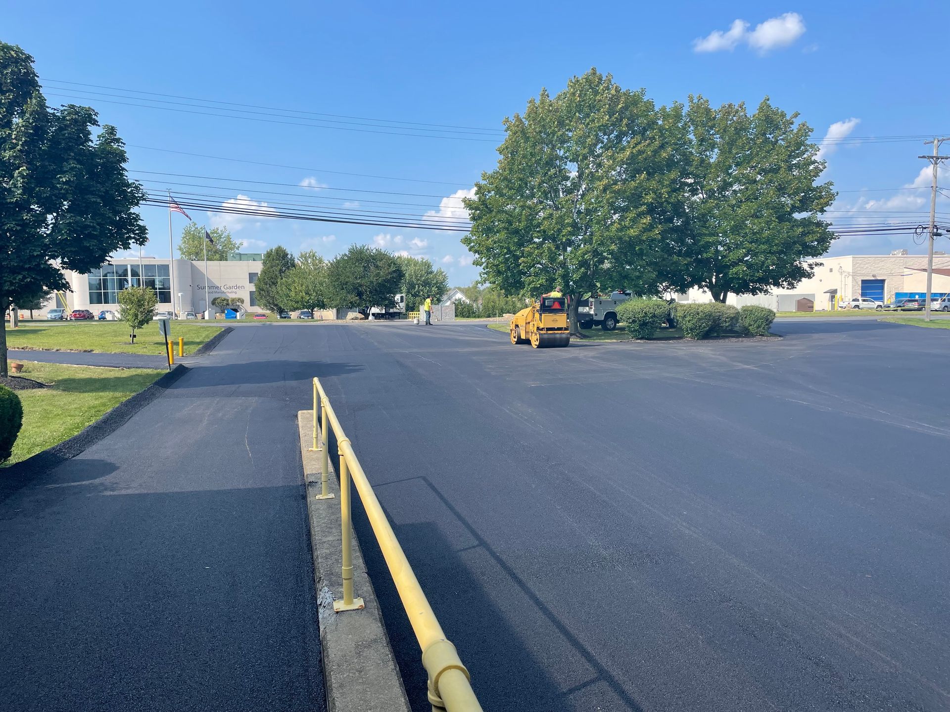 A yellow truck is driving down a road next to a yellow railing.