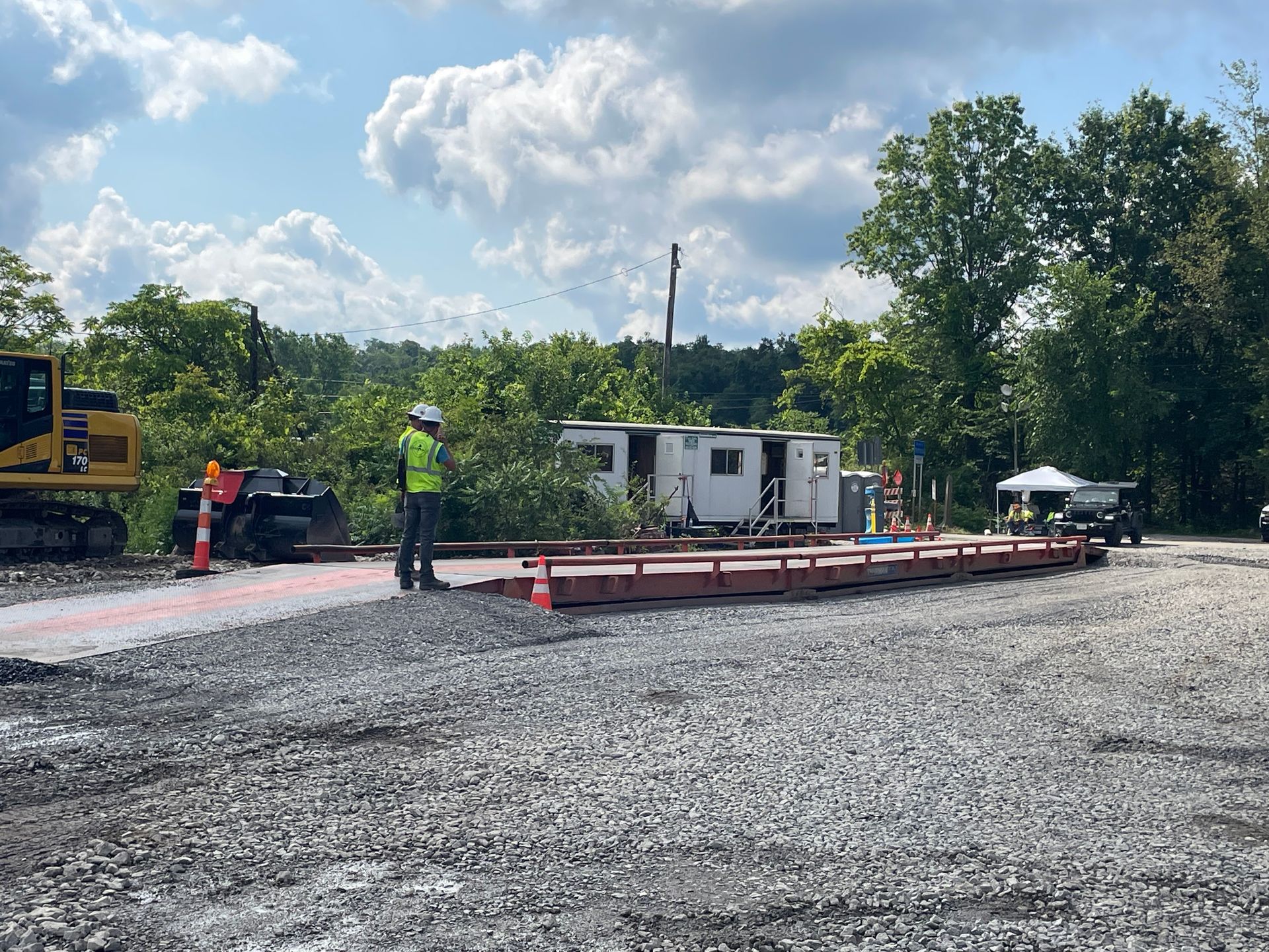 A man in a hard hat is standing on a gravel road.