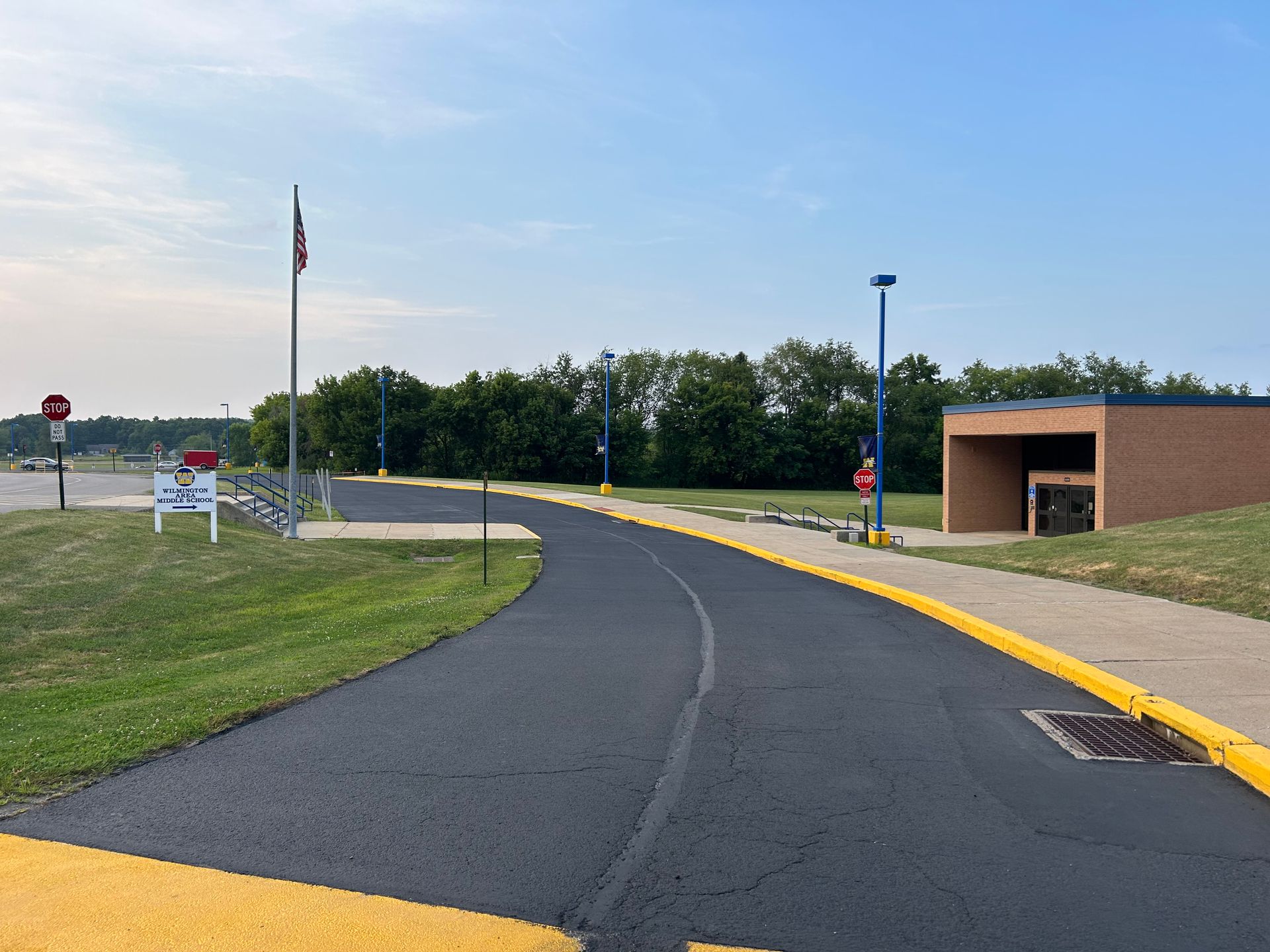 A road with a yellow curb and a building in the background.