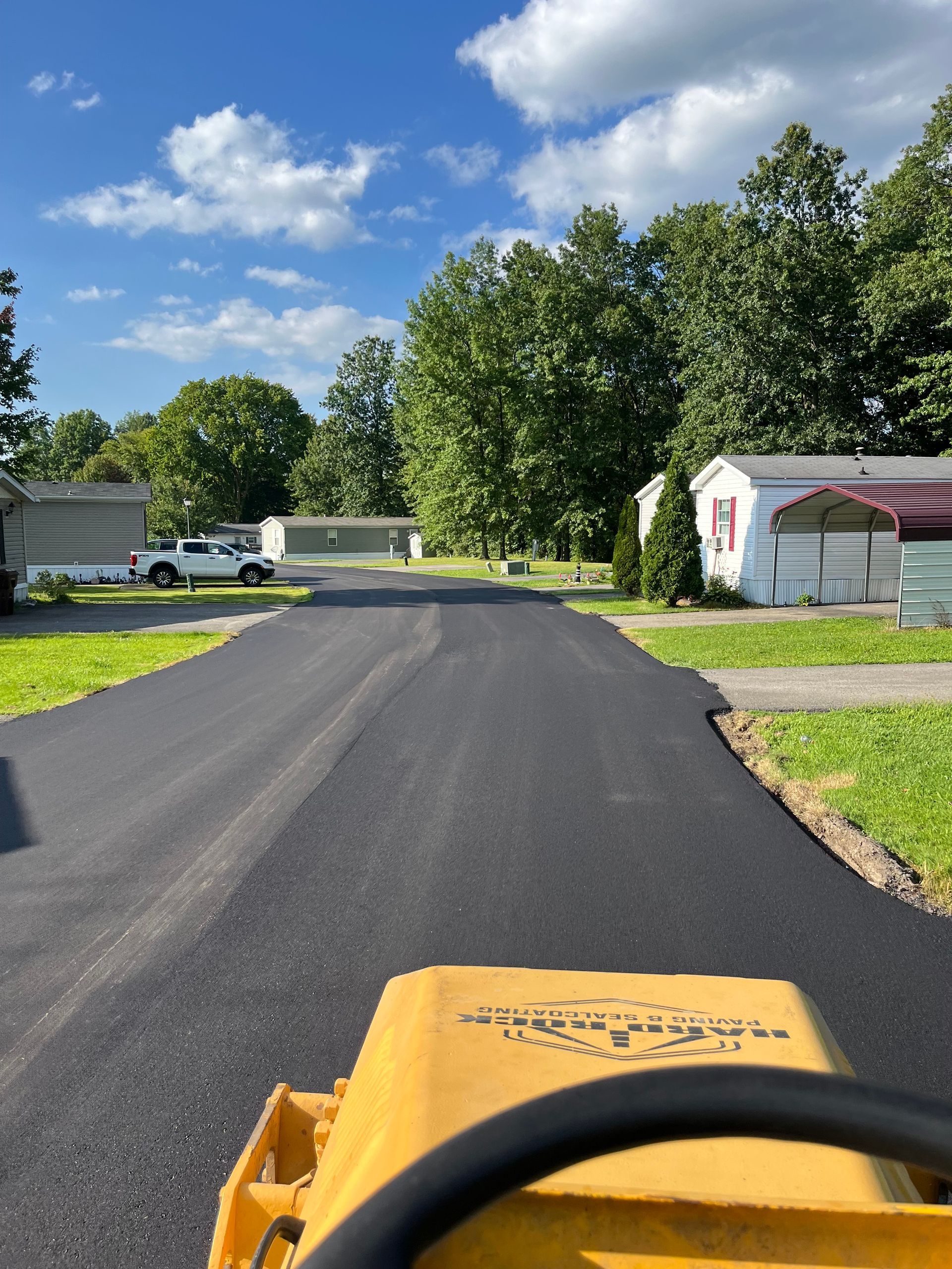 A yellow tractor is driving down a road in a residential area