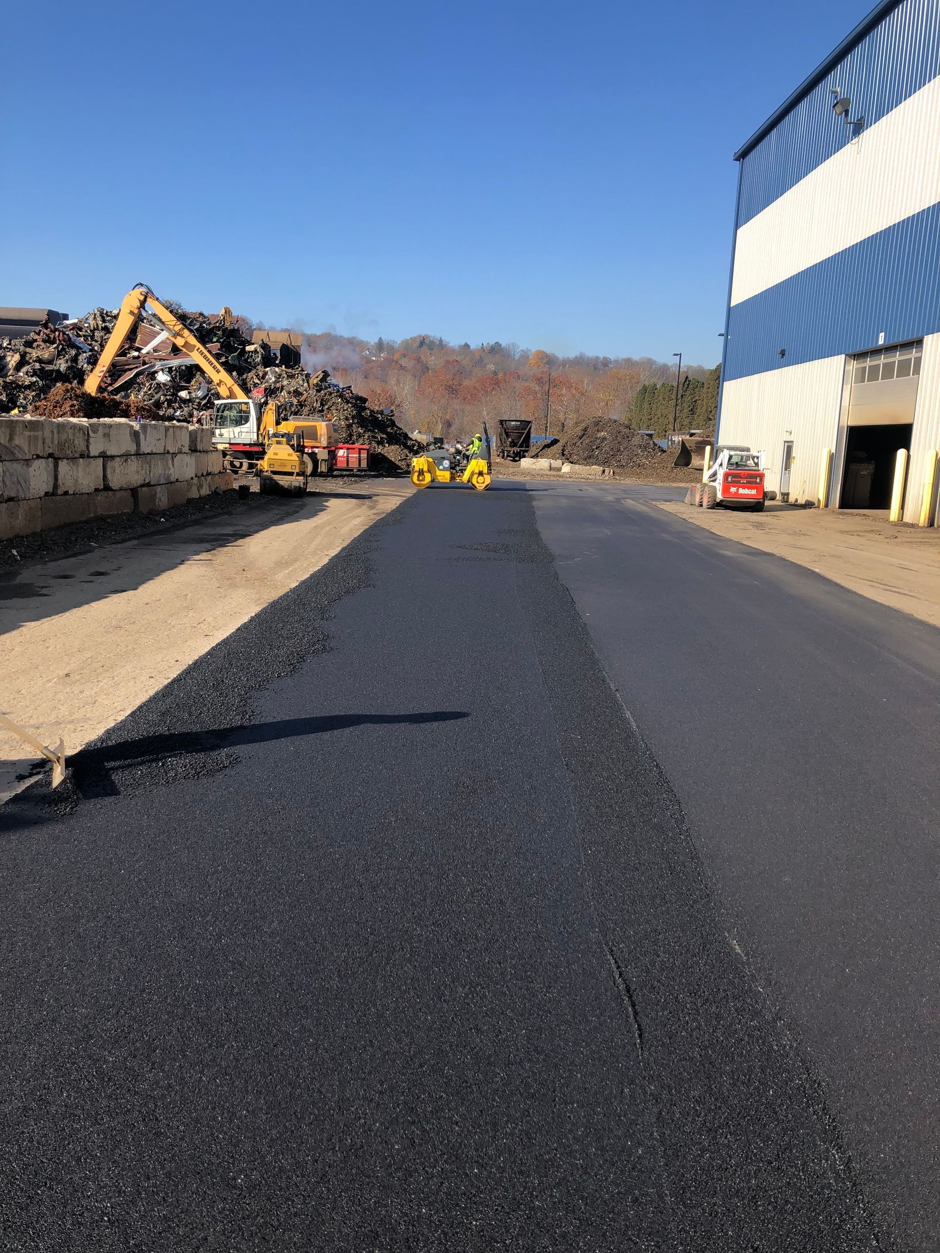 A road is being paved in front of a large building.