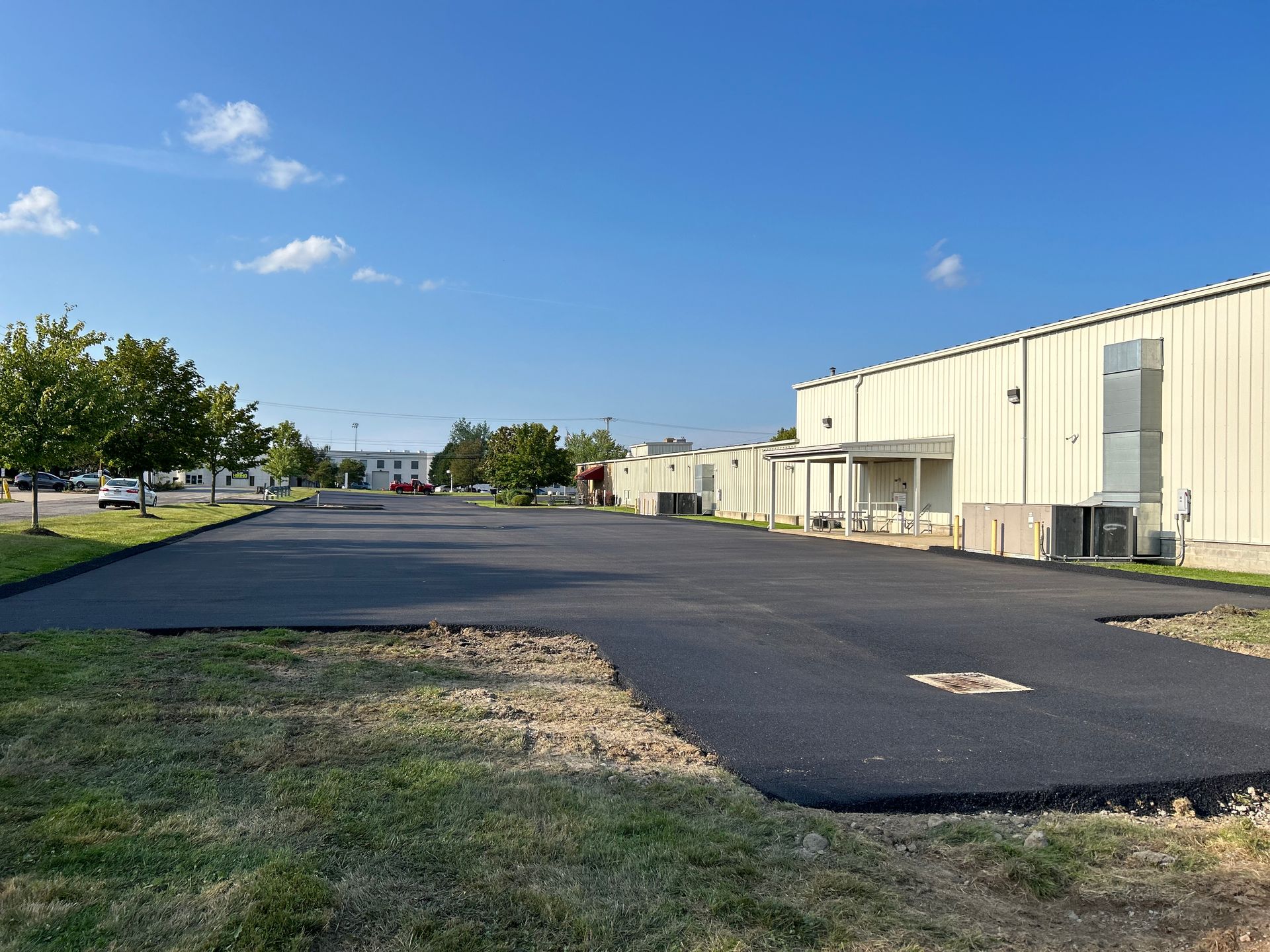 A large warehouse with a lot of asphalt in front of it.