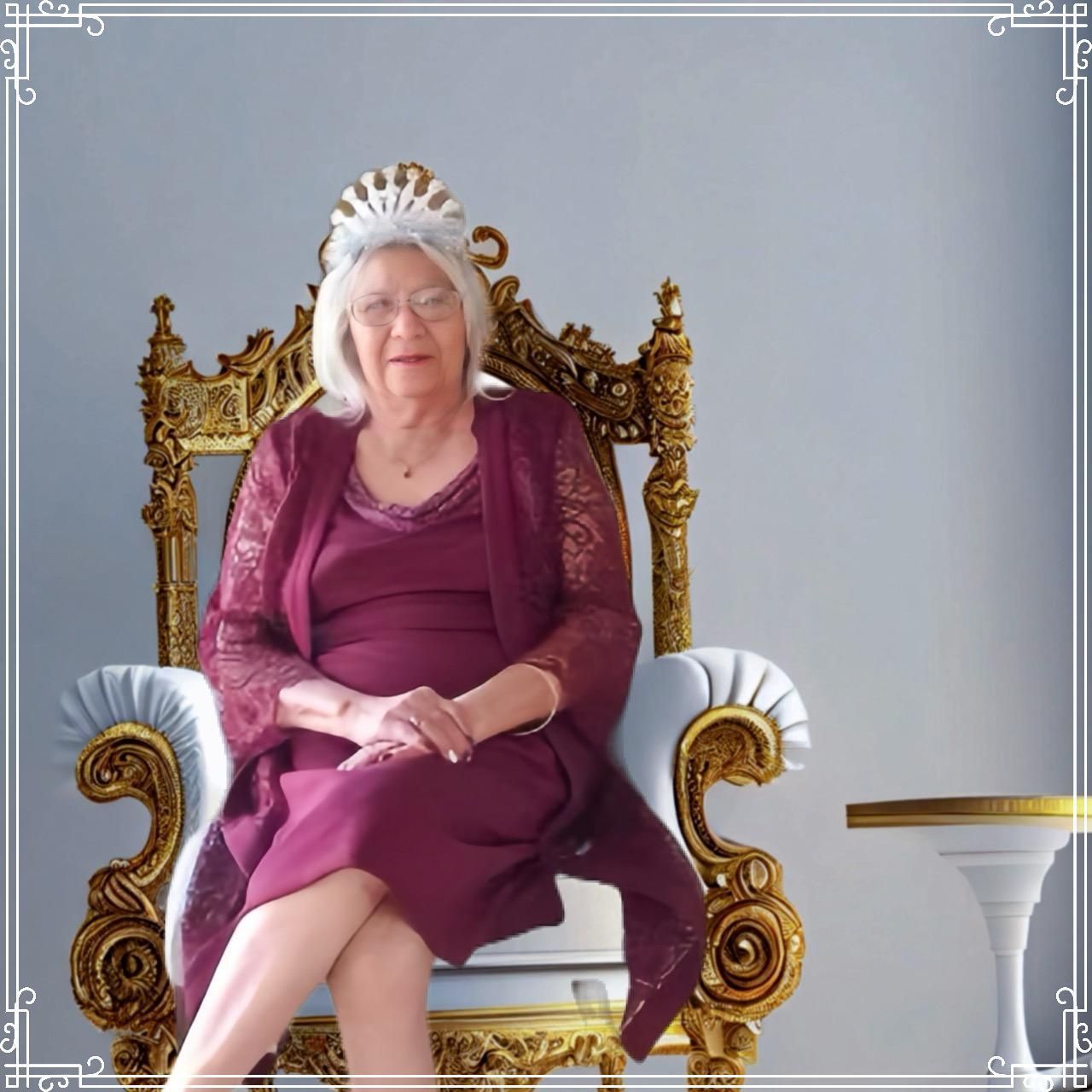 Woman seated on an ornate gold chair against a gray backdrop, wearing a purple dress and white headdress.