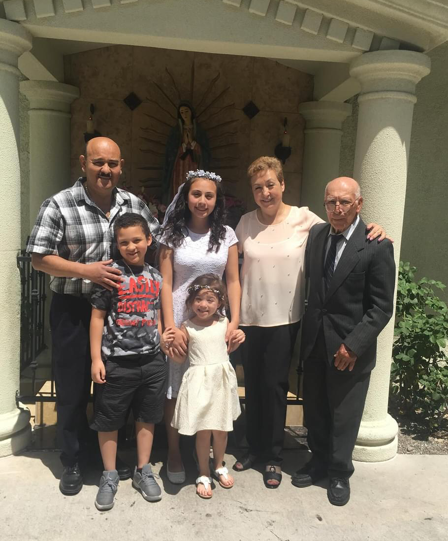 Family of five posing under an archway, with two children in front and three adults behind.