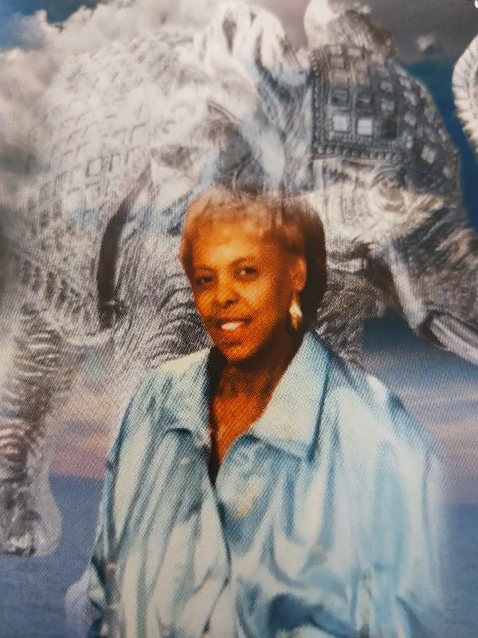 Woman in a blue blouse smiling in front of a large white elephant backdrop.