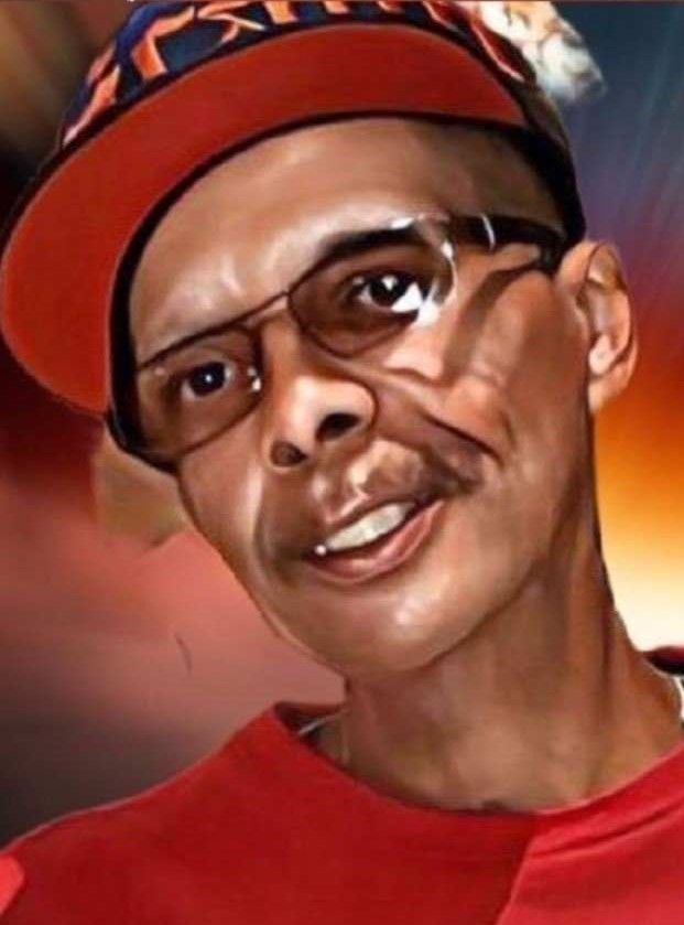 Portrait of a person in a red shirt and cap, wearing glasses, with a slight smile