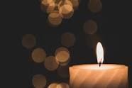 Lit candle on the right with warm bokeh lights in the dark background