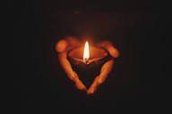 Candles arranged in a heart shape, glowing orange against a dark background