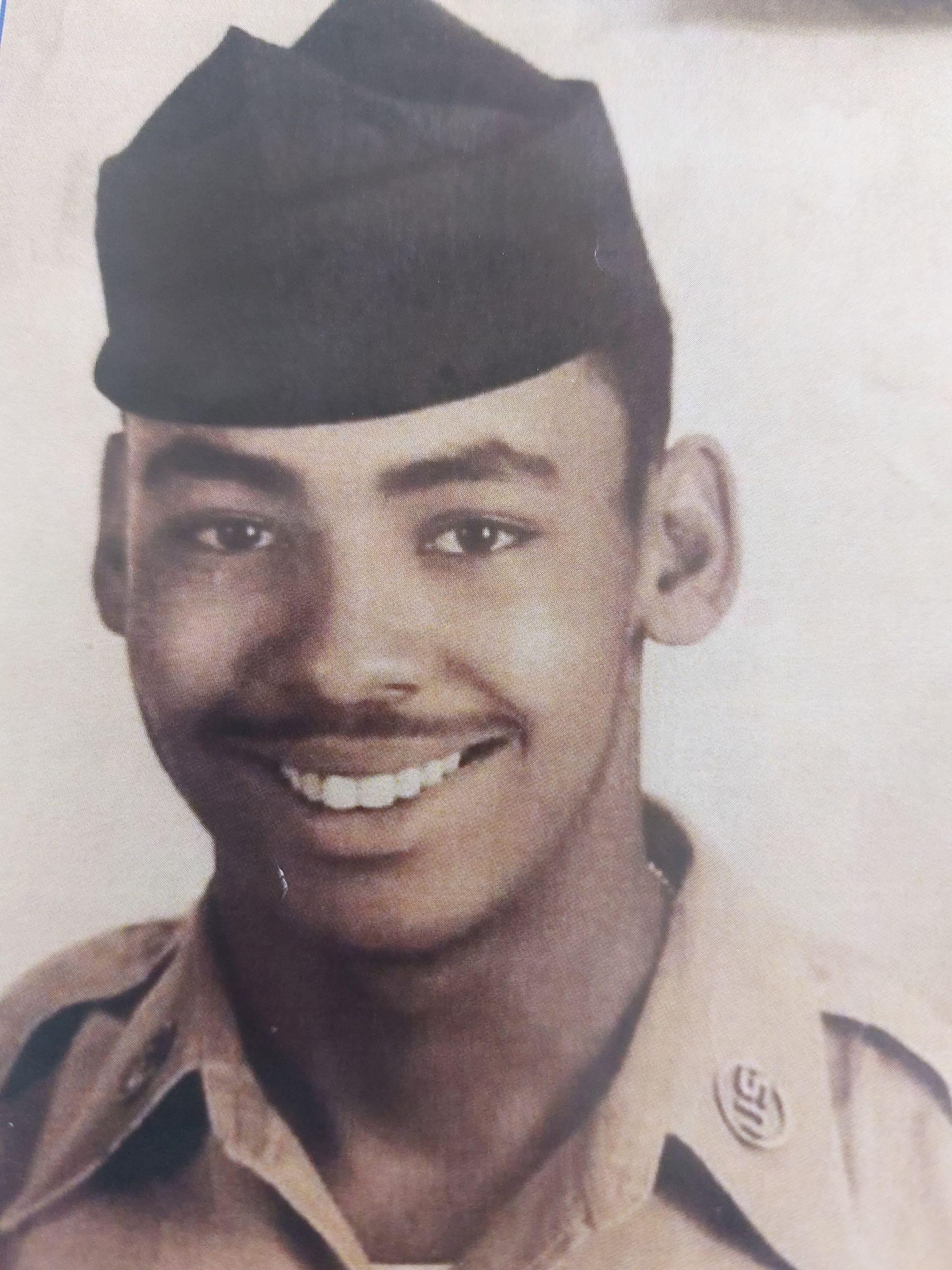 Smiling man in a military uniform and cap, facing forward.
