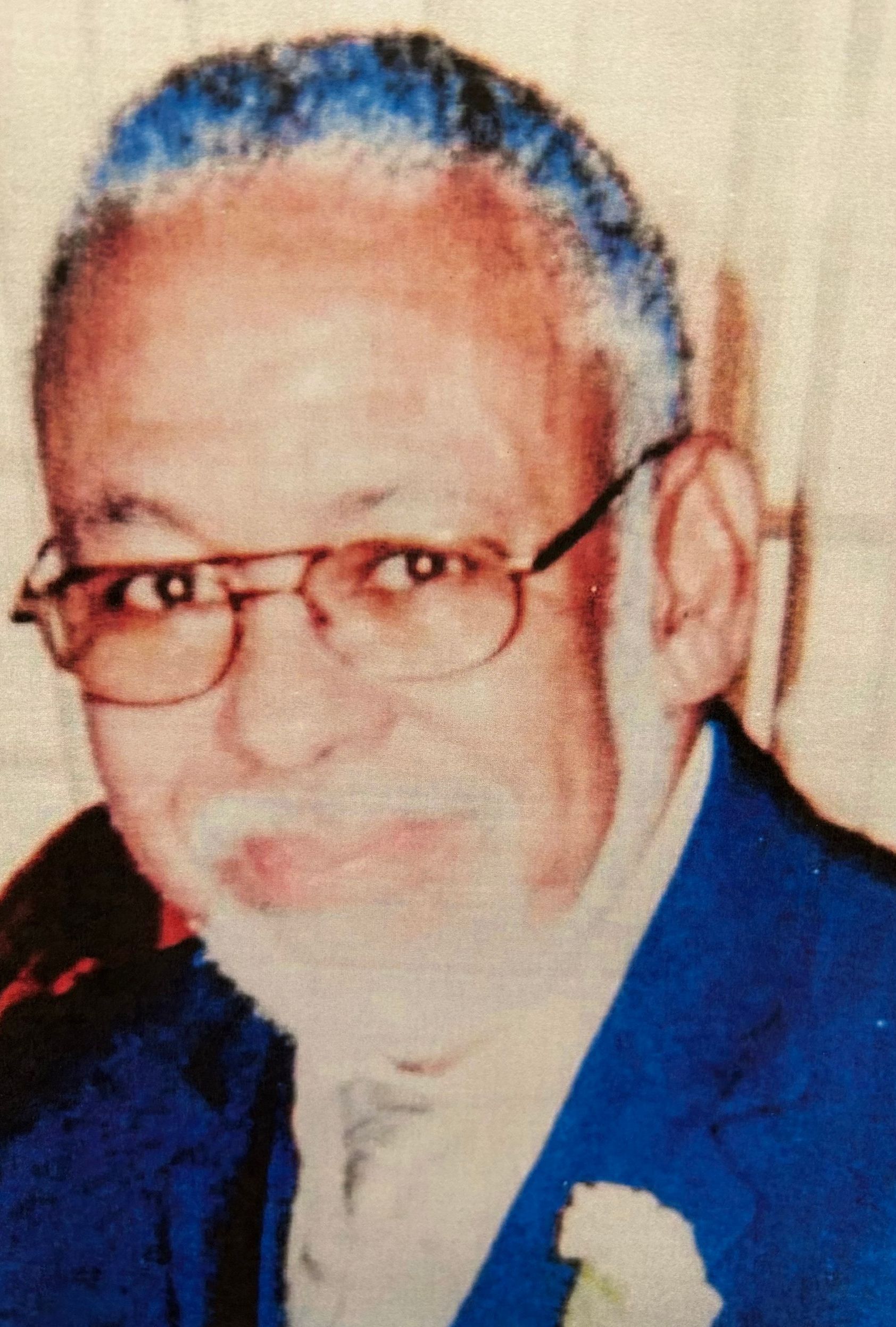 Portrait of a man with glasses and a white beard, wearing a blue suit and white boutonniere