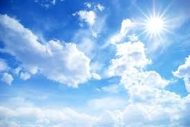 Bright blue sky with fluffy white clouds and the sun shining in the upper right