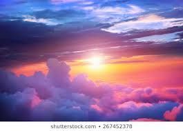 Sunset over pink and purple clouds with bright sunlight and a blue sky