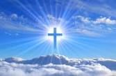 Glowing cross over clouds under a bright blue sky with sun rays