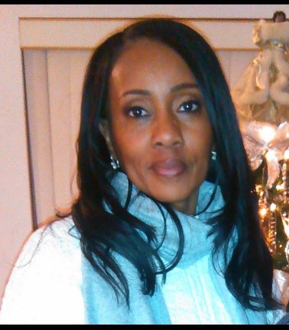 Portrait of a woman in a light blue sweater, standing indoors near a decorated tree.