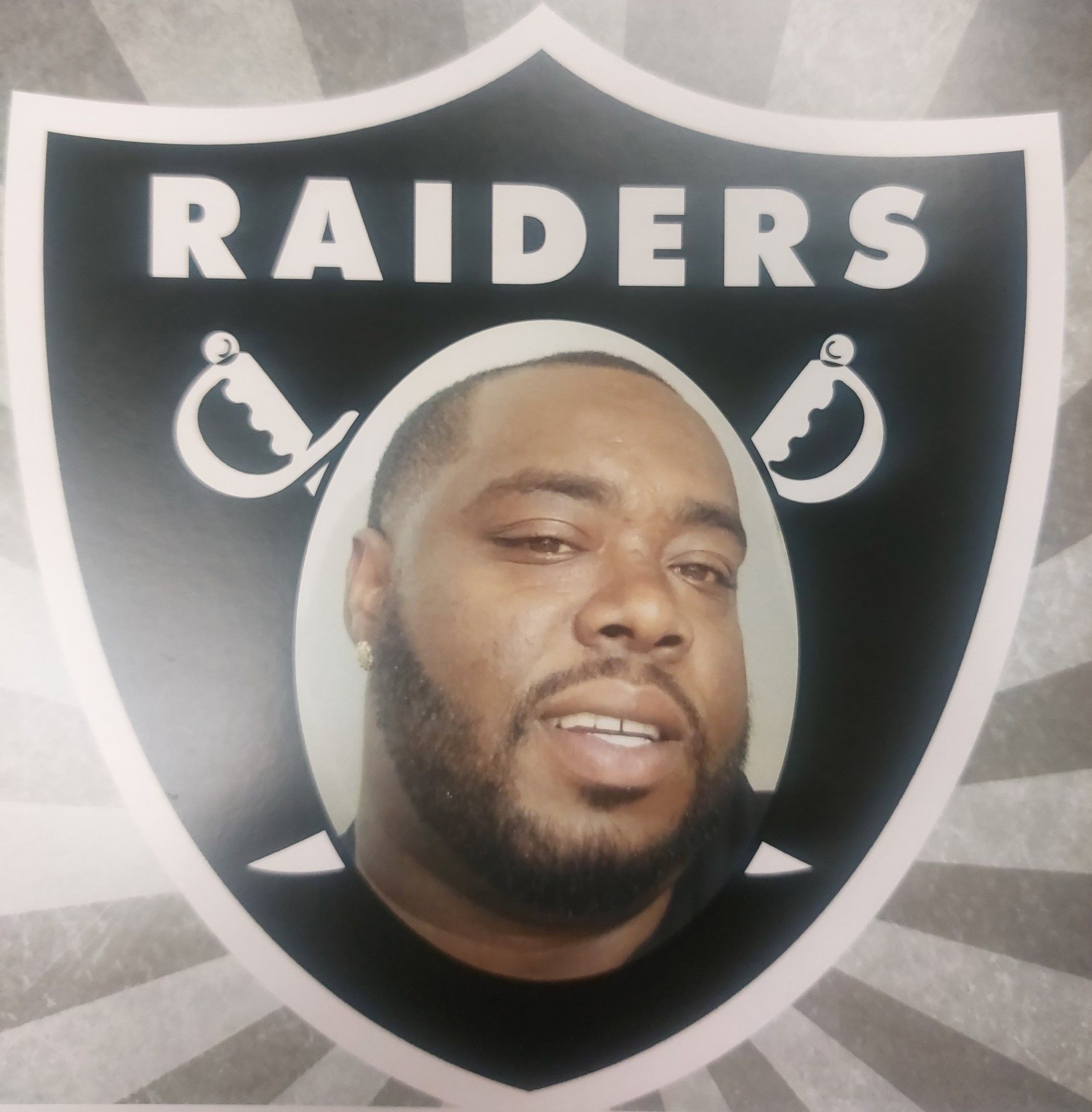 Raiders shield logo with a man's face centered on a black-and-silver background