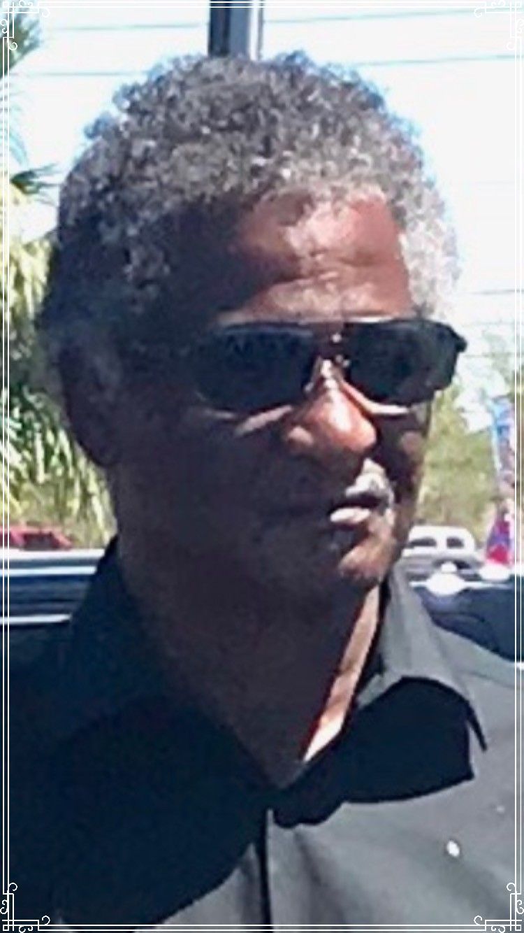 Man wearing dark sunglasses and a black shirt outdoors in bright sunlight