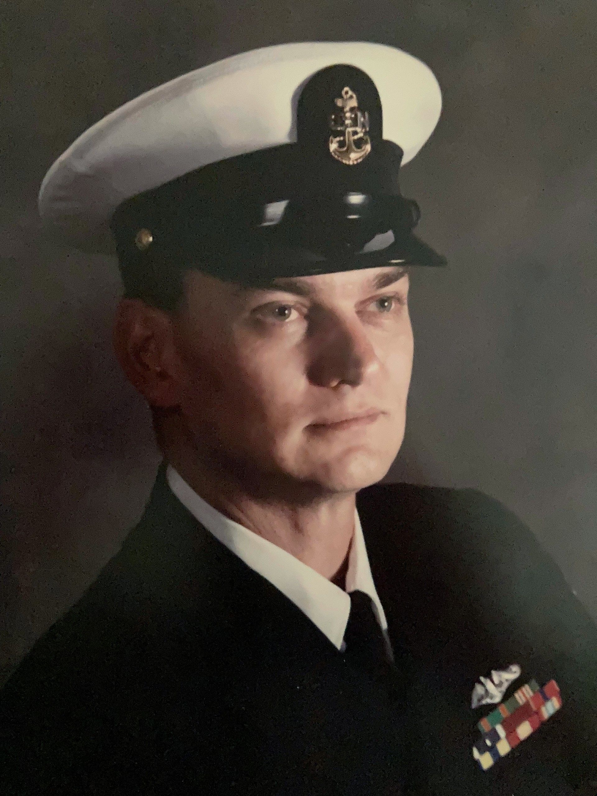 Portrait of a naval officer in dress uniform and white cap, facing left, with medals on his chest