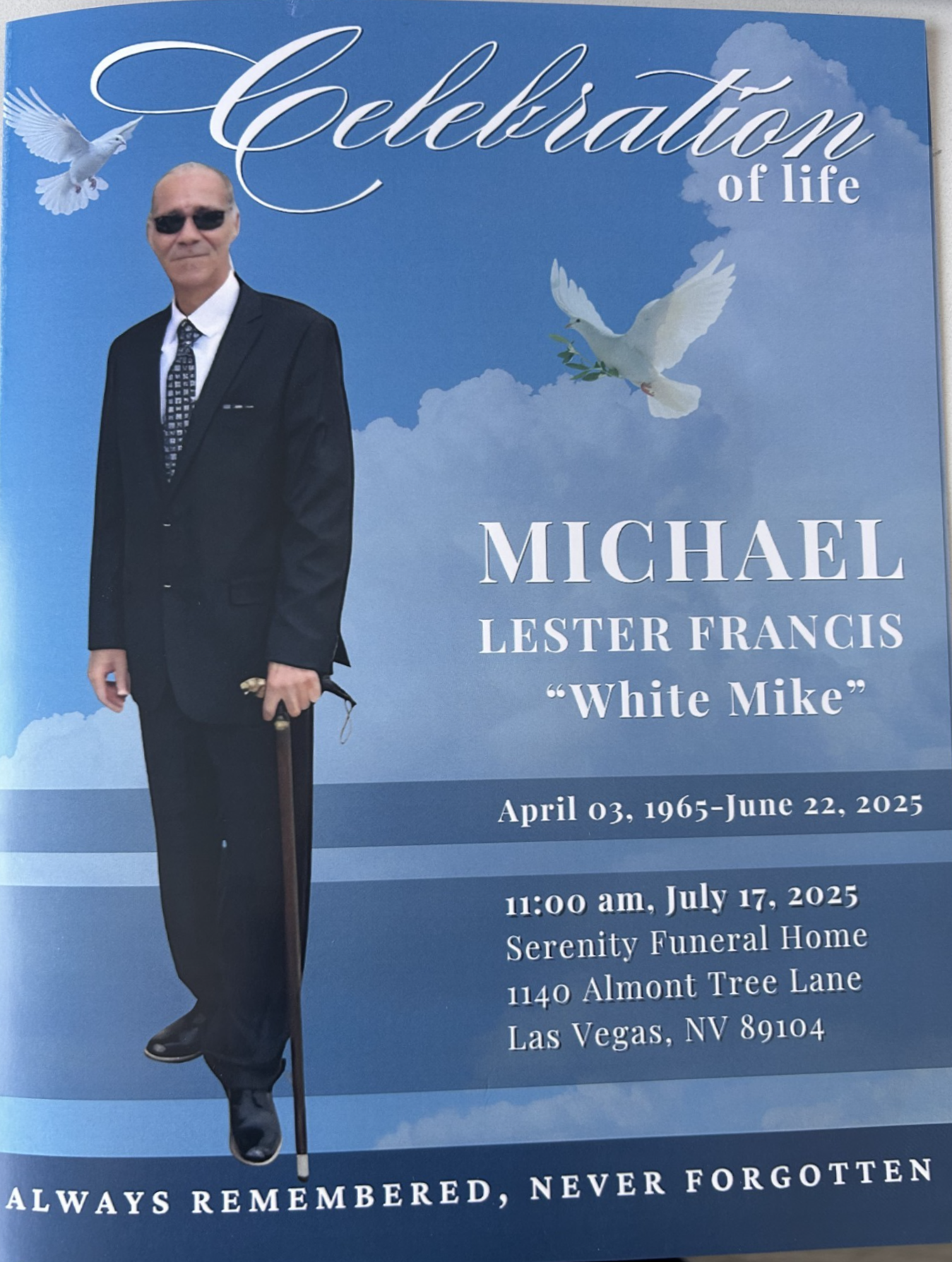 Memorial card with man in black suit, dove, and blue sky background; “Celebration of life” for Michael Lester Francis “Mike”