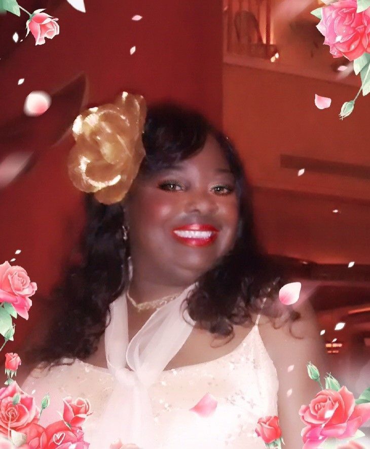 Smiling person in a cream dress with gold flower hair accessory, framed by pink roses and falling petals.