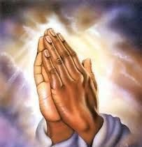 Praying hands clasped together against a glowing light background
