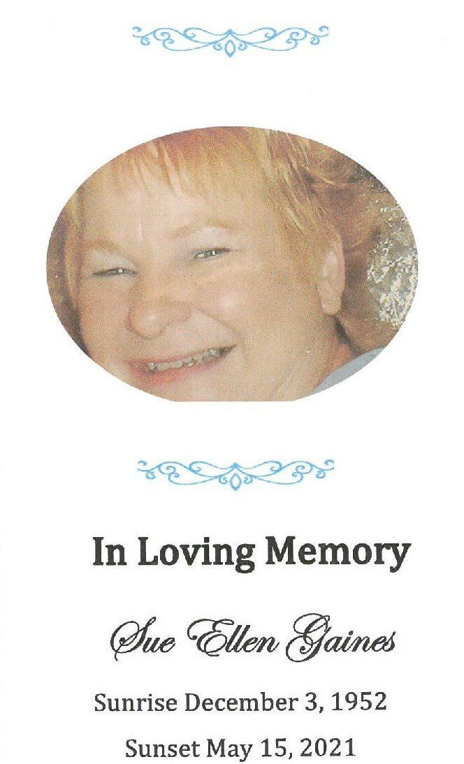 Memorial card with smiling portrait, blue flourishes, and text: “In Loving Memory” and name/date details.