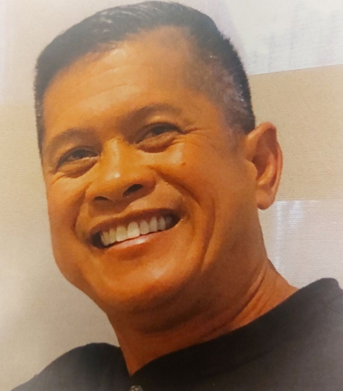 Smiling man in a black shirt against a light background.