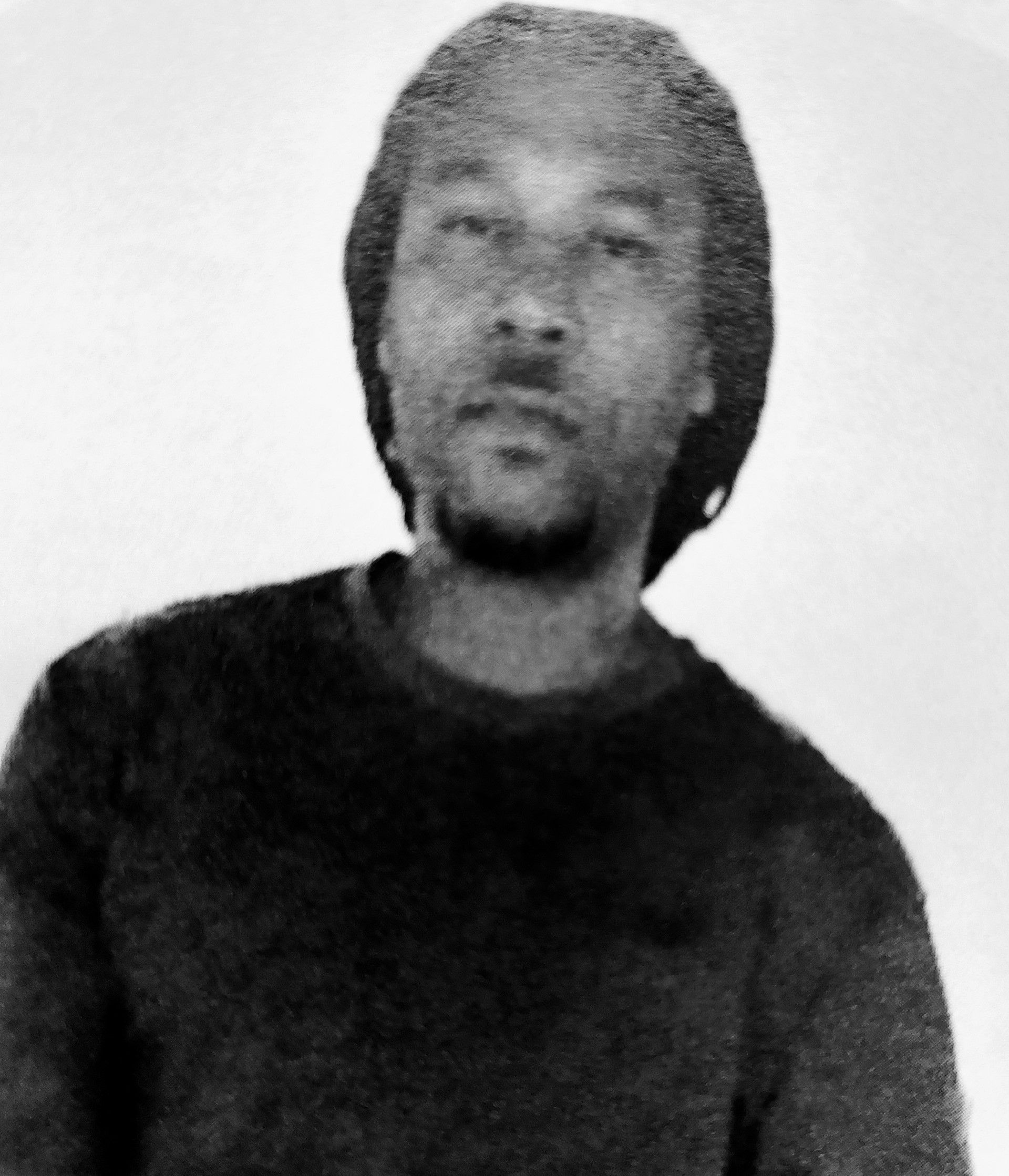 Black-and-white portrait of a person with shoulder-length hair, wearing a dark shirt, against a plain background
