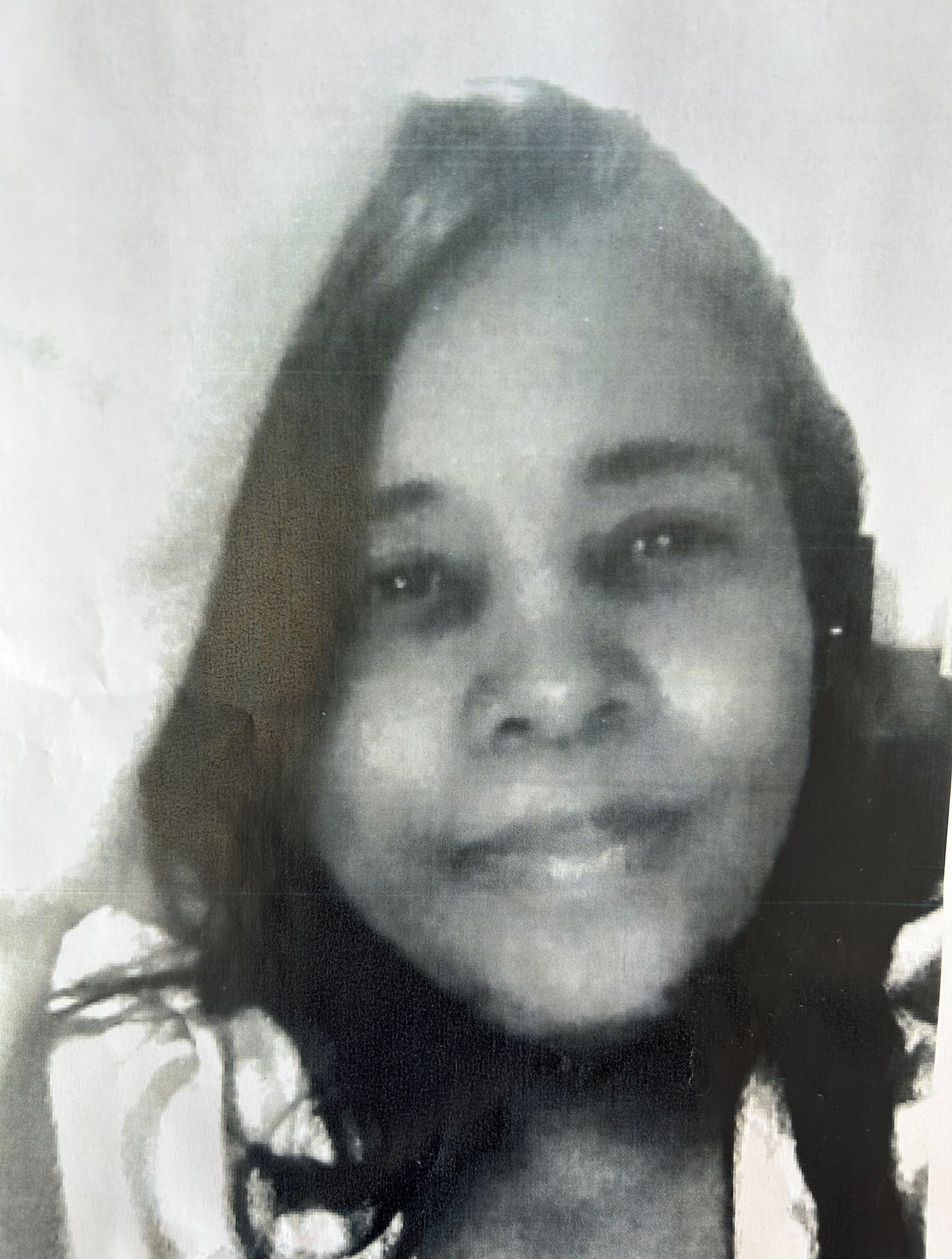 Black-and-white close-up portrait of a smiling person with long hair against a plain background