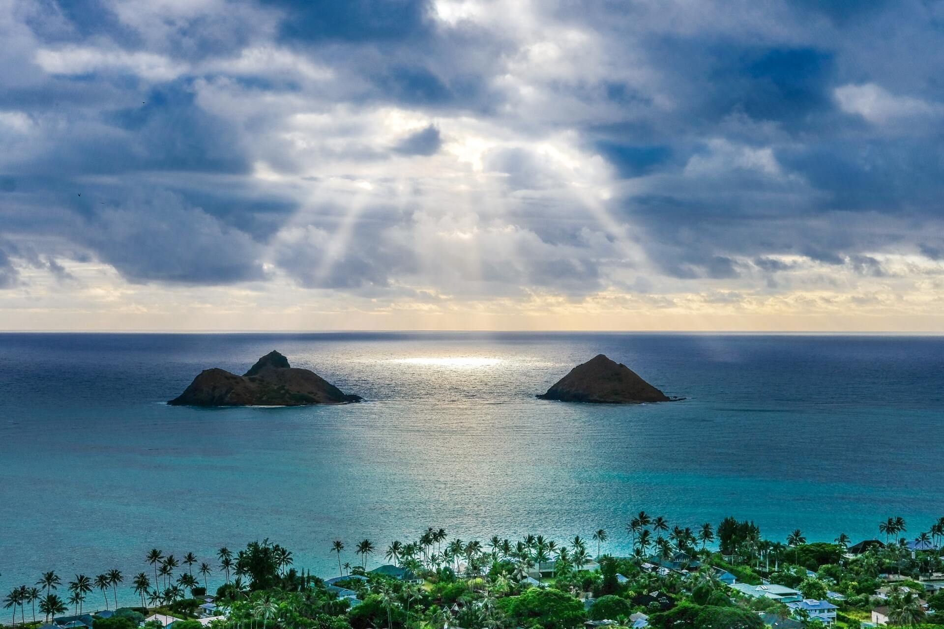 Tropical seascape with two small islands, turquoise water, and a cloudy sky at sunset