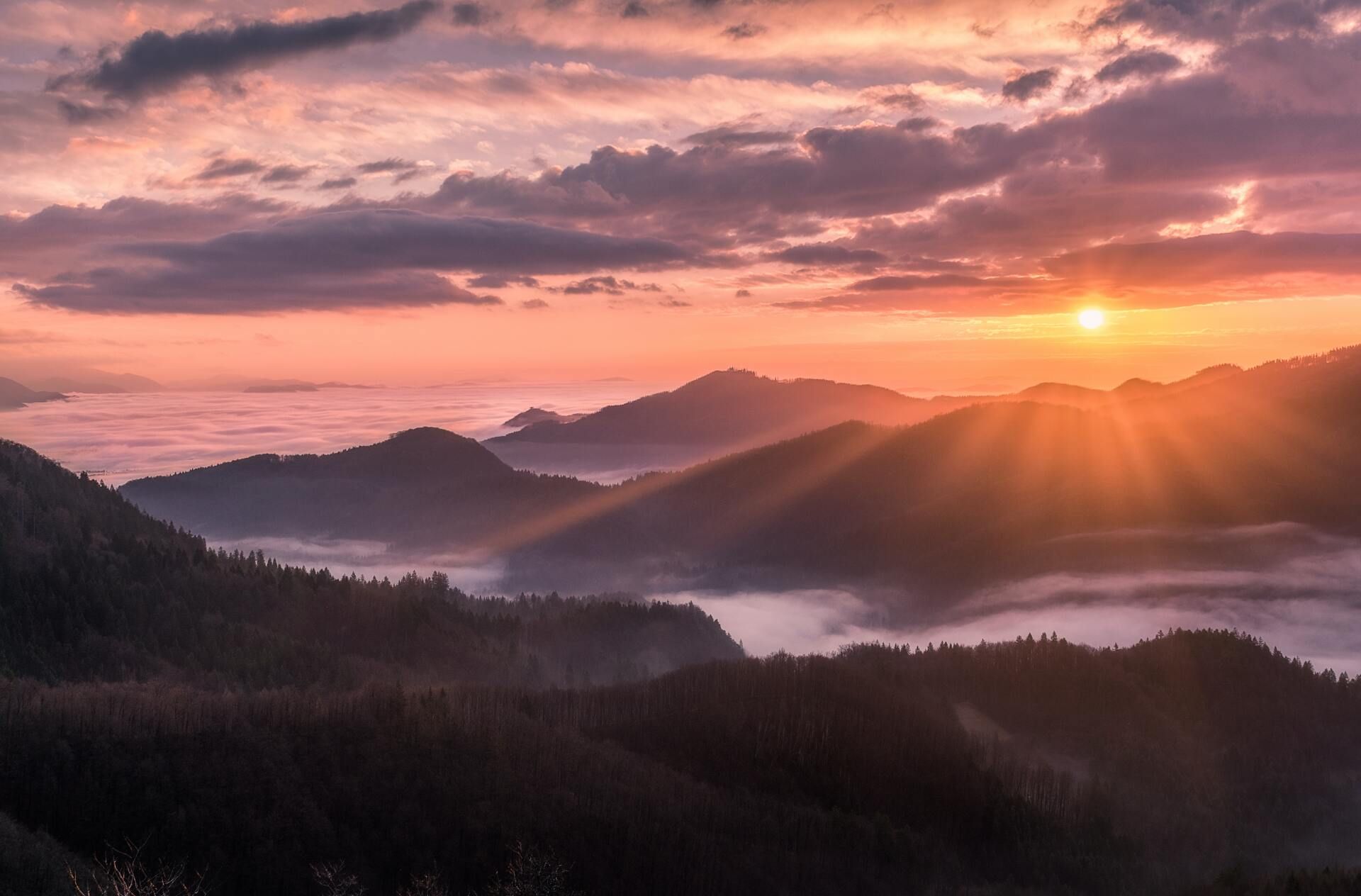 Sunrise over misty mountain ridges with pink clouds and golden light