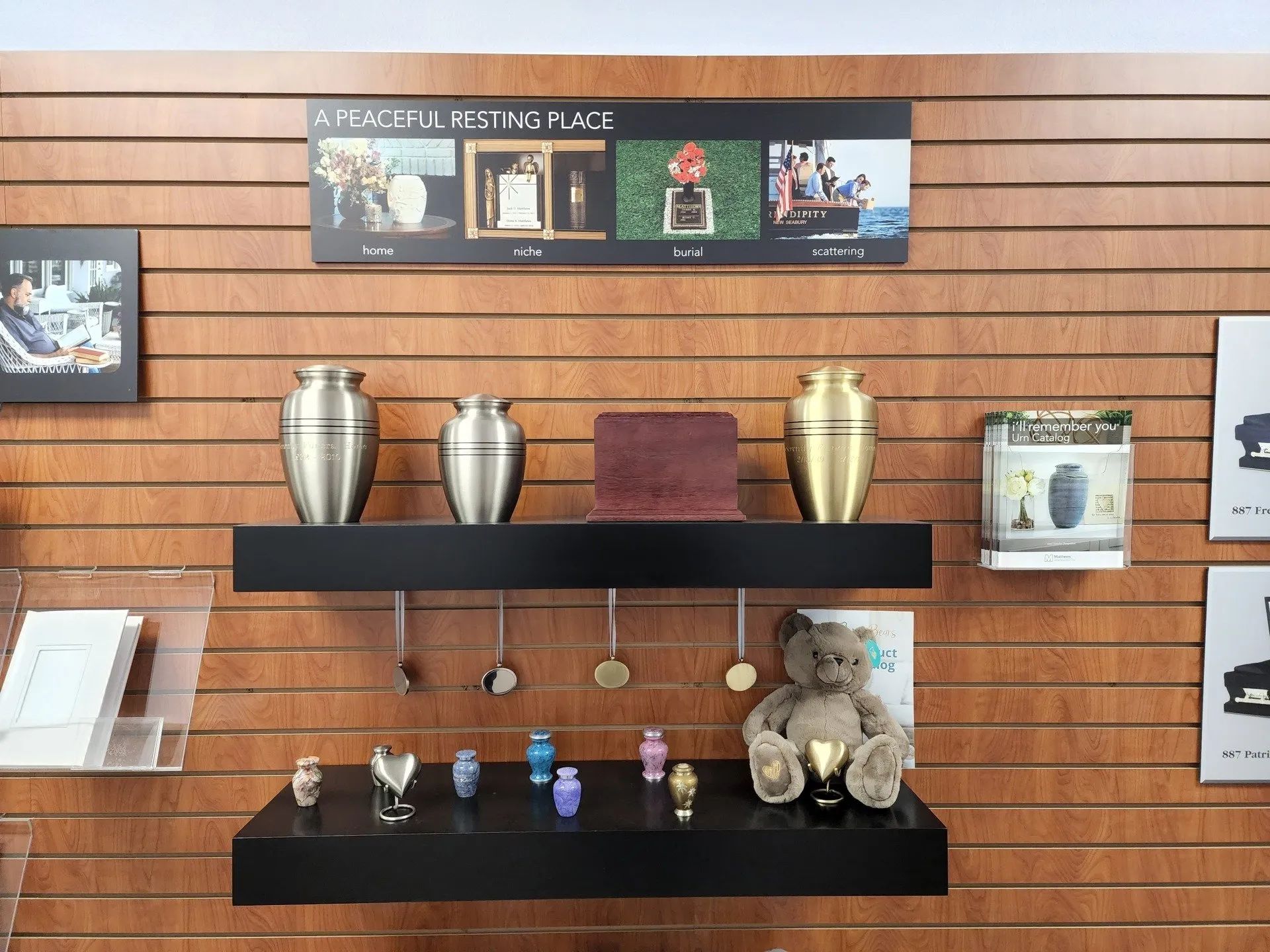 Shelves with urns, small figurines, and a teddy bear on a wood-paneled wall display