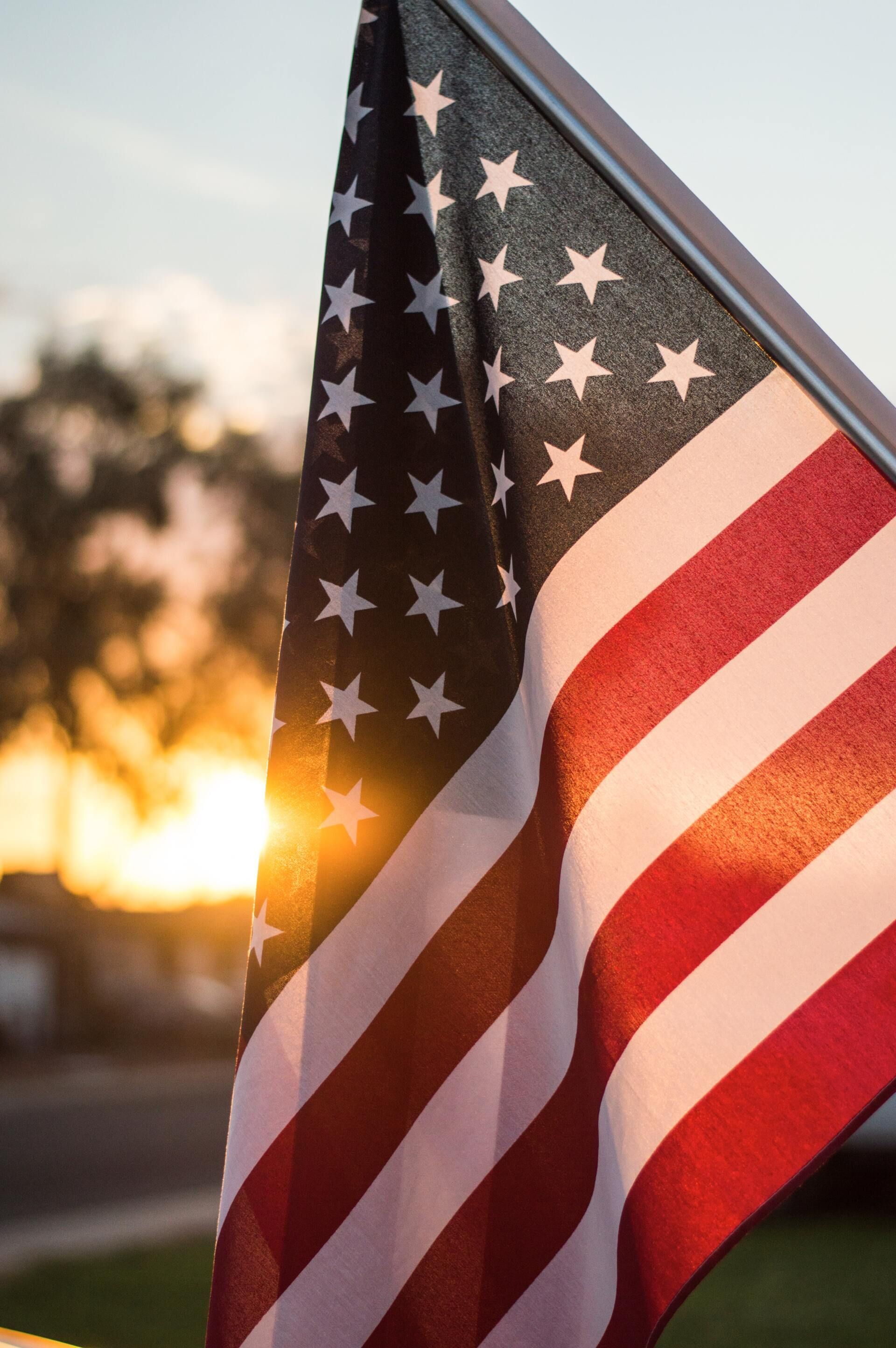 American flag waving at sunset with a blurred background