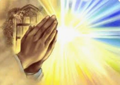 Praying hands in front of a bright cross-shaped light, with blue and gold rays in the background