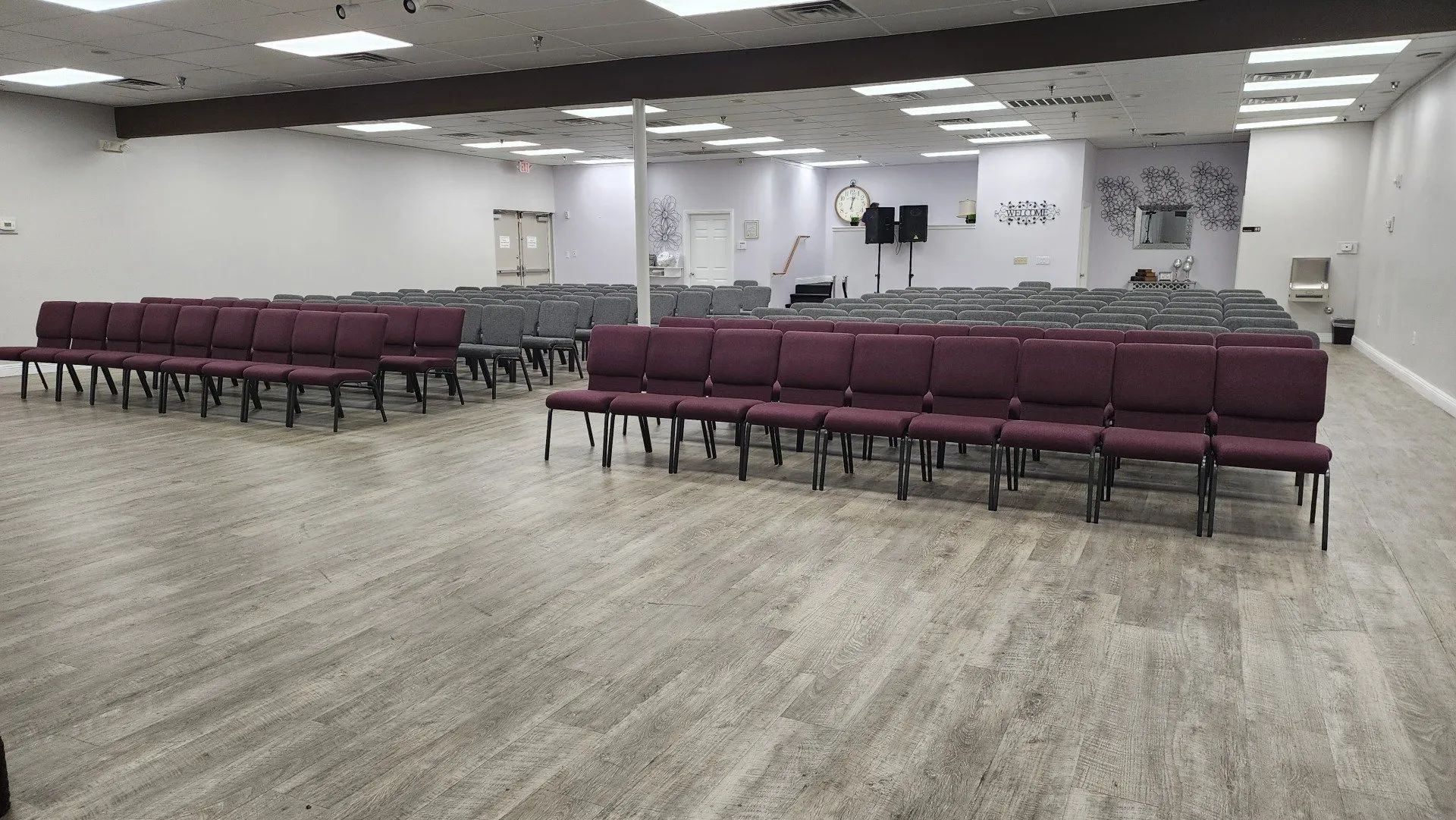 Empty conference room with rows of maroon chairs facing a small stage and screen
