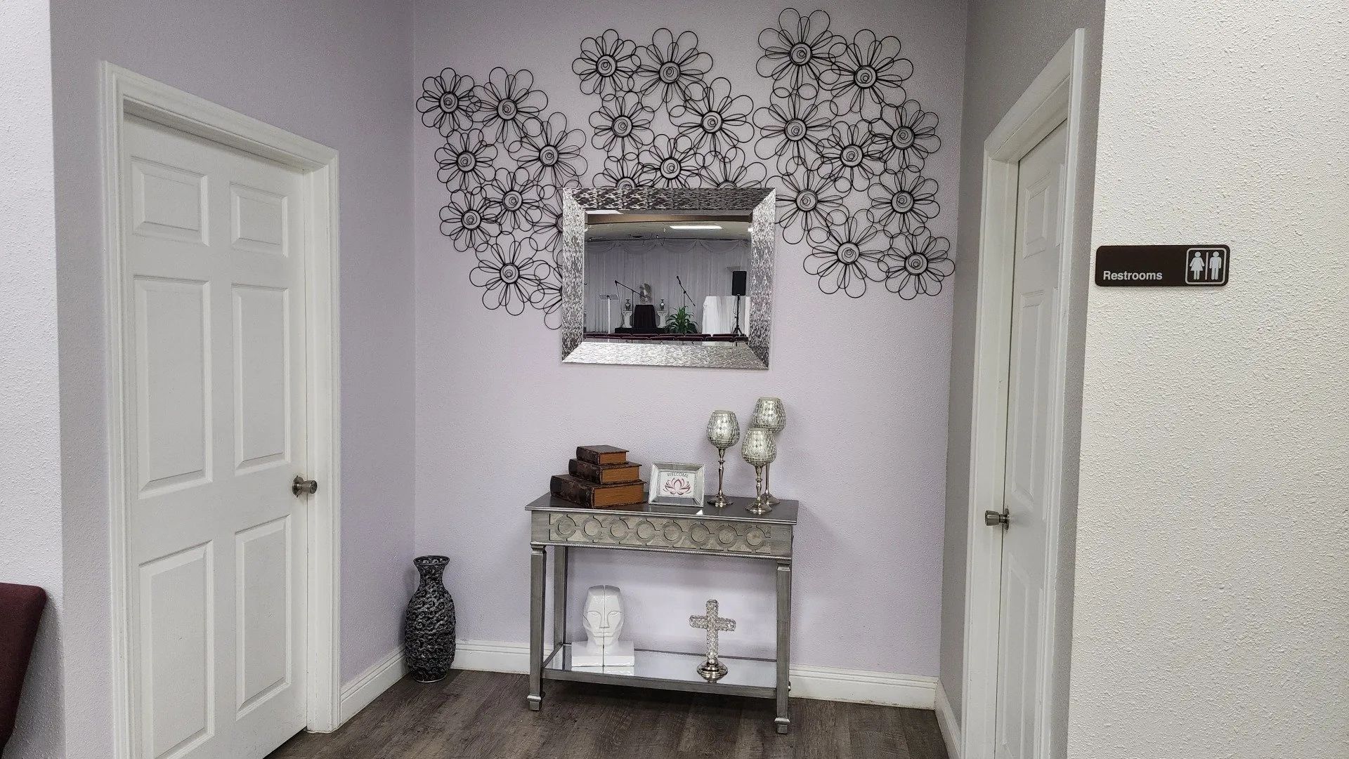 Small entryway with white doors, a decorative console table, and wall art above a mirror.