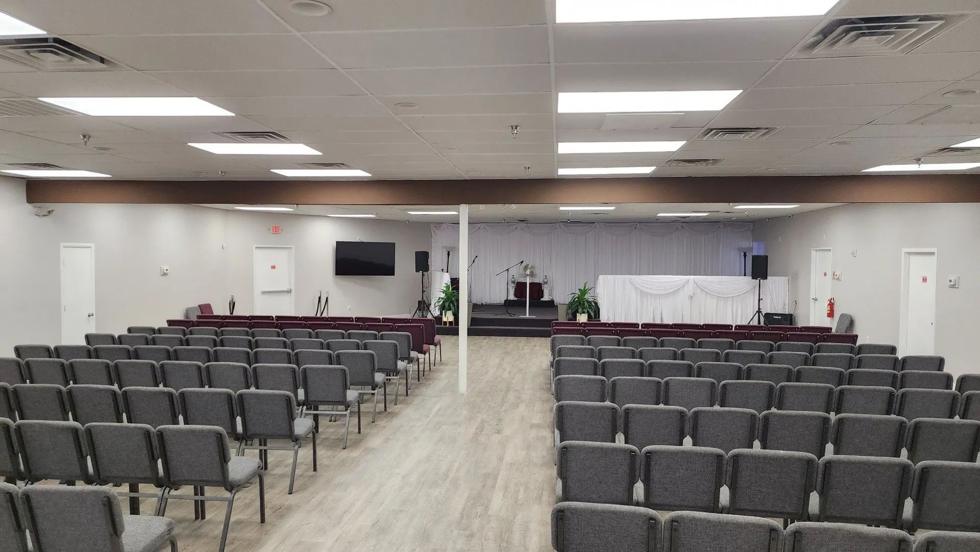 Empty conference room with rows of gray chairs facing a stage and white projection screen