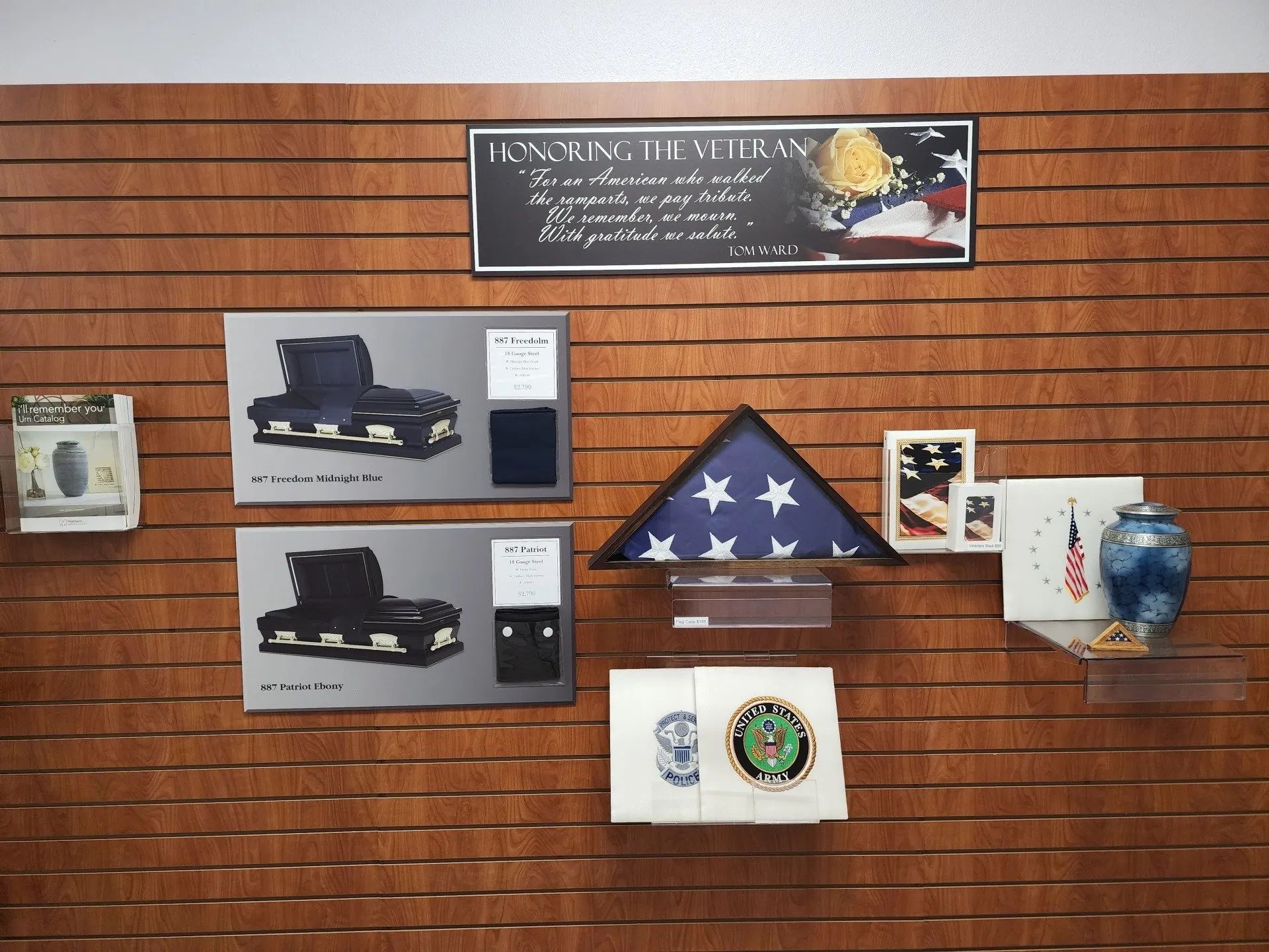 Wall display with framed photos, plaques, a folded American flag, and a commemorative banner.
