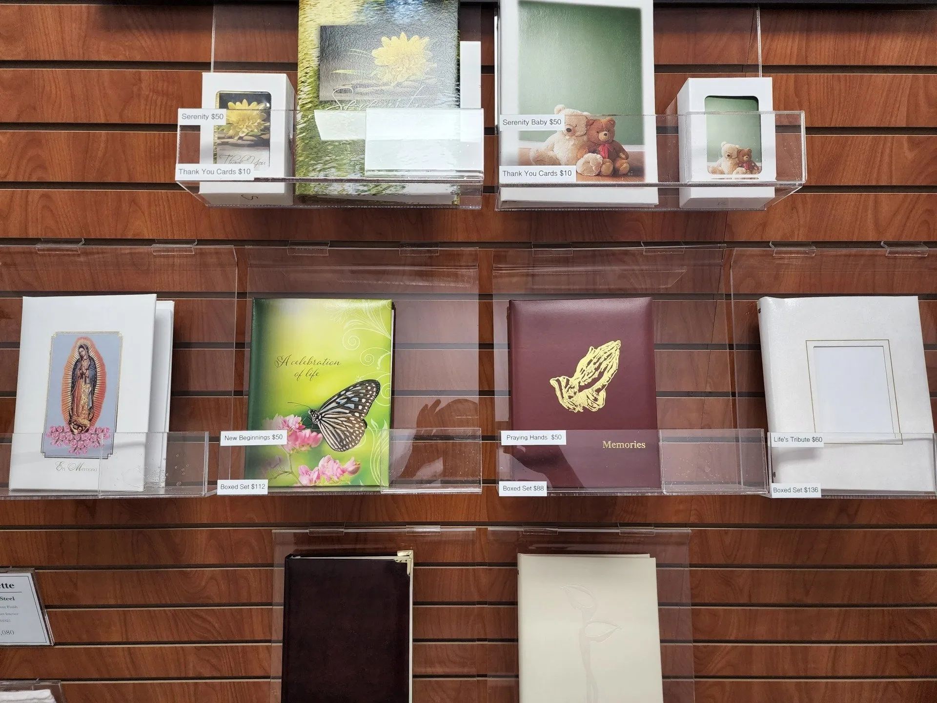 Display shelves with assorted framed art prints and cards against a wooden slat wall.