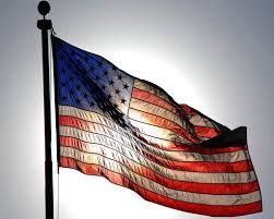 American flag waving on a pole against a bright sky