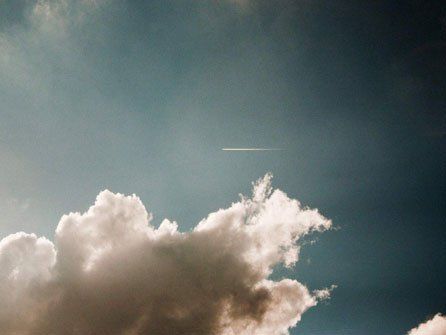 Clouds billowing in a blue sky with a bright sun flare