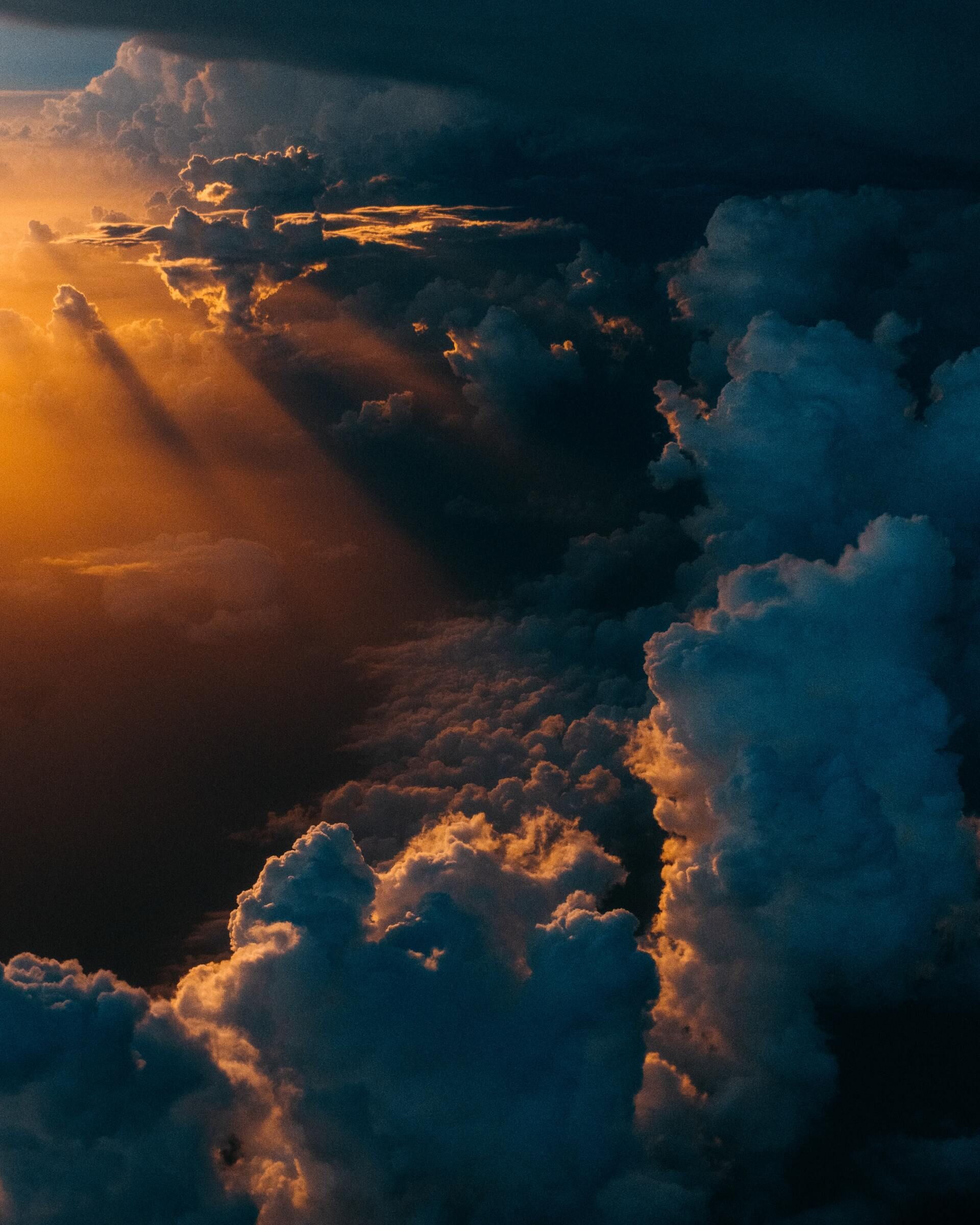 Golden sunlight breaks through dark storm clouds over a dramatic sky.