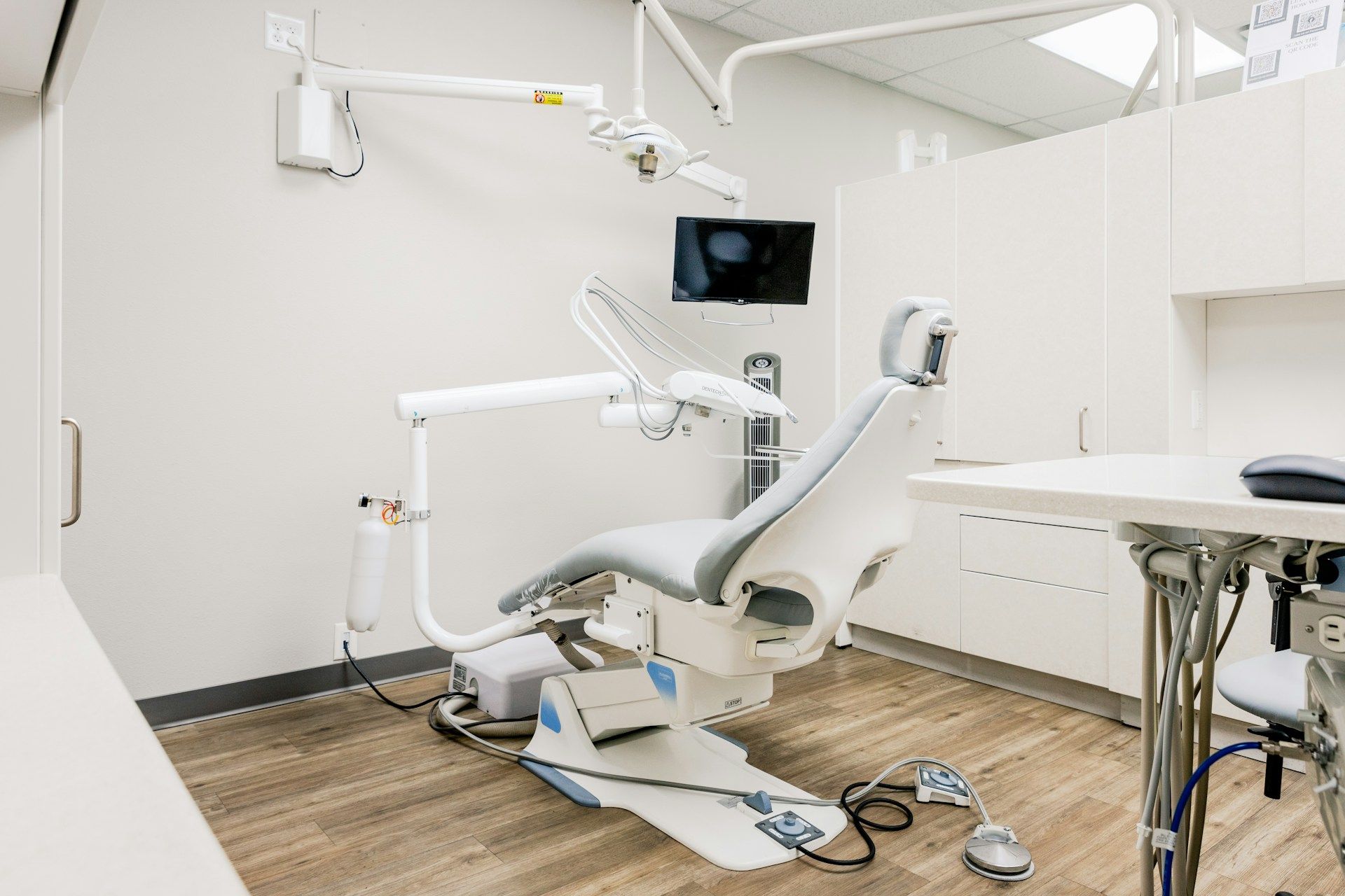 Dental office interior with dental chair, equipment, and cabinets.