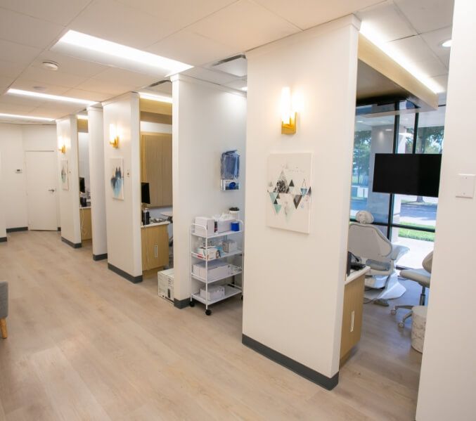 Dental office exam rooms with white walls, light wood floors, and art.