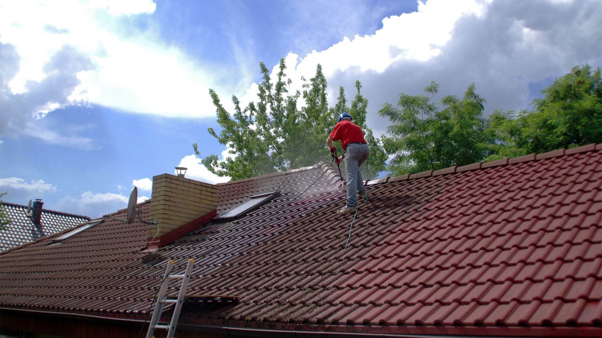 A man is spraying water on the roof of a house