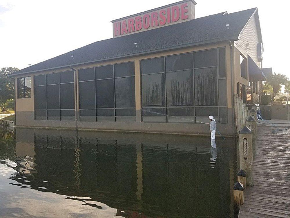 A large building with a screened in porch is surrounded by water.