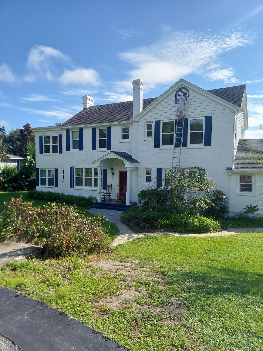 A large white house with blue shutters and a red door