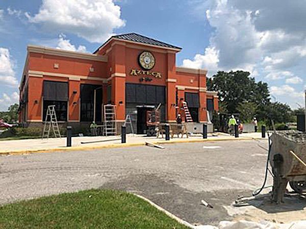 A large orange building with a clock on it is being remodeled.