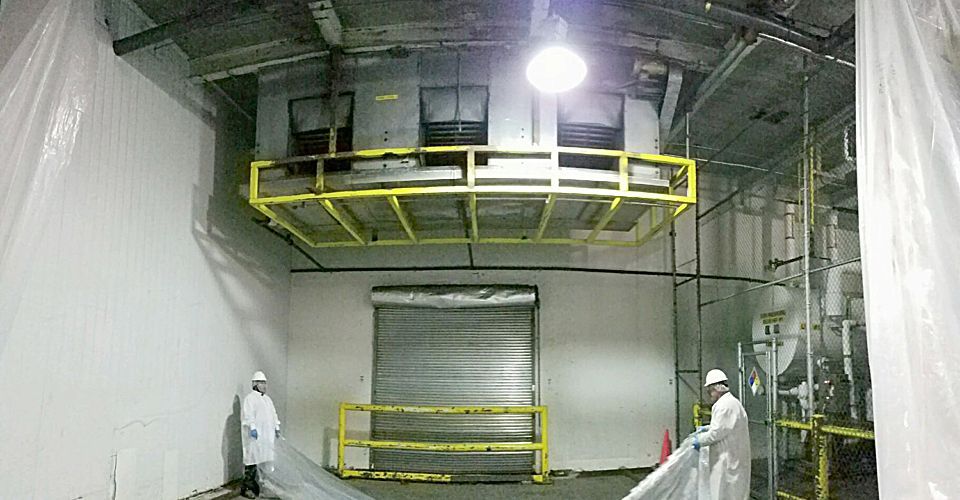 A man in a white suit is standing in a room with a yellow railing.